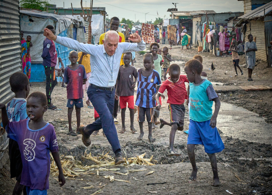 Father Mike Bassano, a Maryknoll priest from the United States, jumps over a ditch as he walks inside the Protection of Civilians area inside the United Nations base in Malakal, South Sudan.  Some 35,000 people live in the camp, protected by UN peacekeeping troops. They were displaced from Malakal following the outbreak of a civil war in 2013. The armed conflict has a strong element of ethnic tension, and the mostly Shilluk and Nuer residents of the camp fear for their security from the largely Dinka population that has moved into their former town.  Bassano, also a member of Solidarity with South Sudan, an international network of Catholics supporting the new country, lives in the camp.